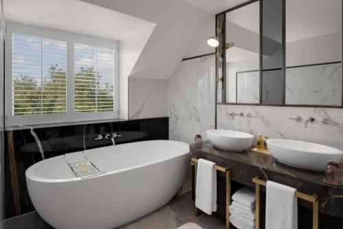 a bathroom with a large white tub and two sinks at The Biltmore Mayfair in London