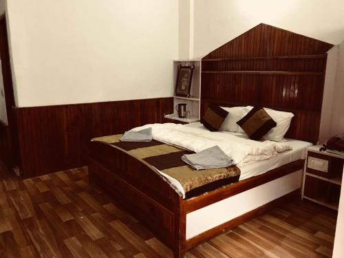 um quarto com uma cama grande e uma cabeceira em madeira em Tarun Residency em Saharanpur