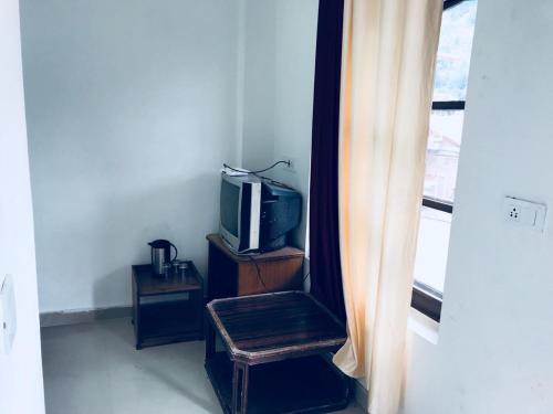um quarto com uma televisão e um banco ao lado de uma janela em Tarun Residency em Saharanpur