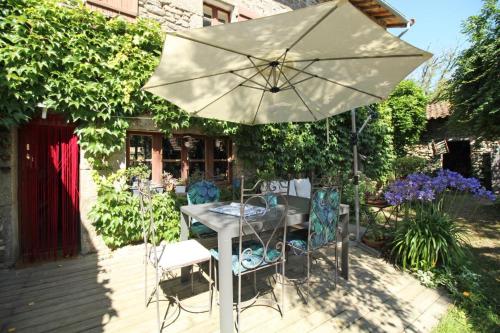 a table and chairs under an umbrella on a patio at Kernad in Bersac-sur-Rivalier