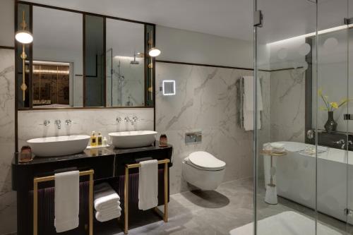 y baño con 2 lavabos, aseo y bañera. en The Biltmore Mayfair, en Londres