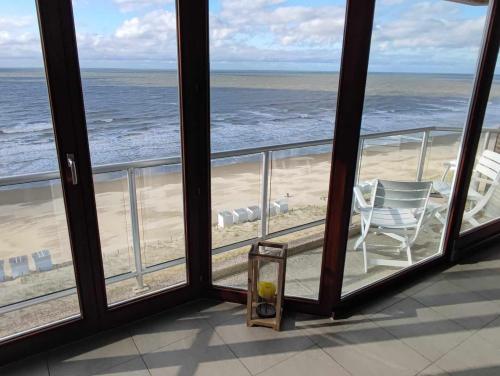 a room with a view of the beach and a chair at LUXURY APP, frontal sea View + south terrace + garage in Middelkerke