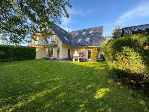 una casa con un patio con césped verde y una casa en Ostseegarten Nienhagen, en Ostseebad Nienhagen