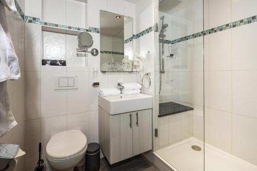 a bathroom with a toilet and a sink and a shower at Hotel Gruenberger in Berchtesgaden