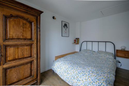 une chambre avec un lit et une commode en bois dans l'établissement Maison Calme Proche Métro L11, à Montreuil