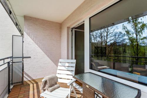 a balcony with a glass table and a chair at Berg und Tal Apartment in Brilon