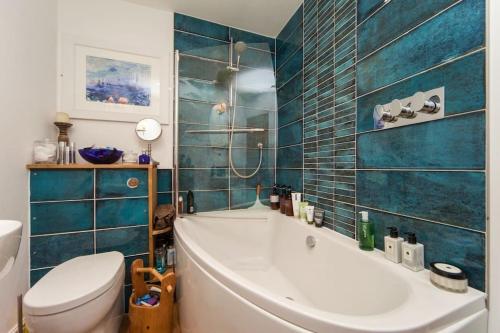 巴德來索特頓的住宿－Nomi Homes - Budleigh Salterton - Beach - Sleeps 4，带浴缸和卫生间的浴室以及蓝色瓷砖。
