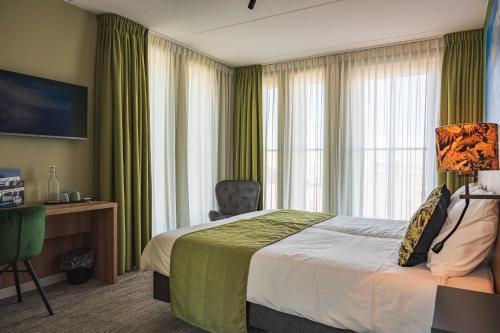 a hotel room with a bed and a desk and window at Schierzicht Logement in Lauwersoog