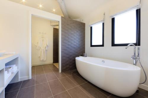 a bathroom with a large white tub and a window at Château Rasque - Teritoria in Taradeau