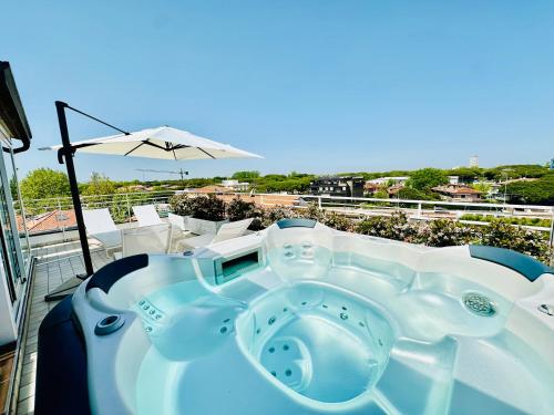 un bain à remous sur un balcon avec un parasol dans l'établissement Hotel Miramare - SPA & Suites - Breakfast & Brunch Until 13-00, à Cervia