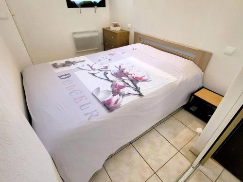 Una cama blanca con flores en una habitación en Appartement Six-Fours-les-Plages, 2 pièces, 4 personnes - FR-1-316-16, en Six-Fours-les-Plages
