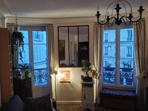 un salon avec un lustre et deux grandes fenêtres dans l'établissement Apartment Gugu Montmartre, à Paris