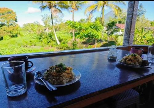 two plates of food on a table with a view at Talaga Tomohon Home Stay and Fishing Pond in Tomohon