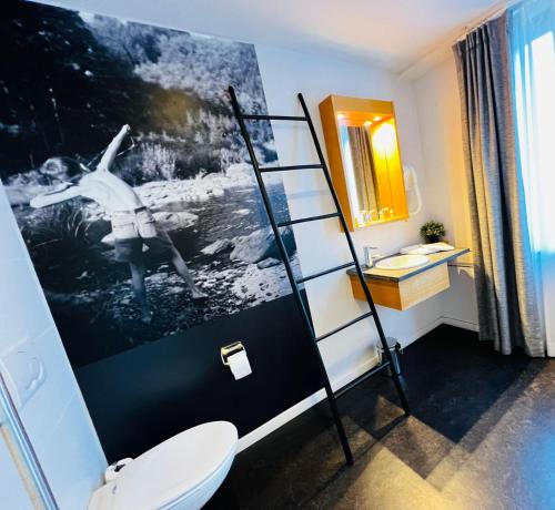 サン・テュベールにあるホテル ヴァル デ ポワのバスルーム(トイレ付)が備わります。壁に絵が描かれています。