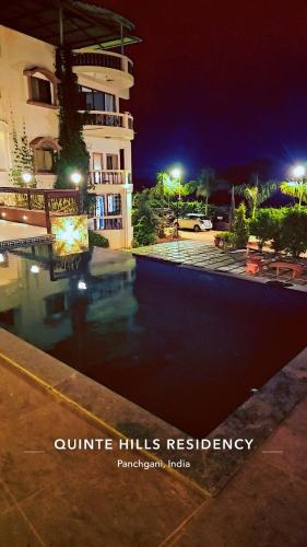 a swimming pool in front of a building at night at Quinte Hills Residency in Panchgani