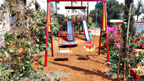 a playground with a slide in a garden at Quinte Hills Residency in Panchgani