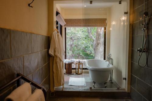 ein Bad mit einer Badewanne, einem Waschbecken und einem Fenster in der Unterkunft Aloof Jungle Lodge in Ghānerao