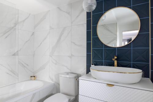 a bathroom with a tub and a toilet and a mirror at Hotel Elysées Bassano in Paris