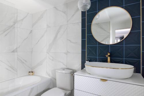 W łazience znajduje się wanna, toaleta i lustro. w obiekcie Hotel Elysées Bassano w Paryżu