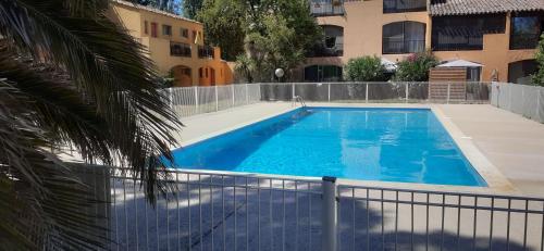 une piscine bleue entourée d'une clôture dans l'établissement Studio 24 m2 - Hameaux de Camargue - village 9 - 13200 Arles, à Arles