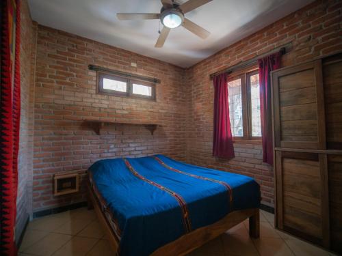 um quarto com uma cama azul e uma parede de tijolos em 2 bedroom apartment with bay view, deck and roof terrace em San Juan del Sur