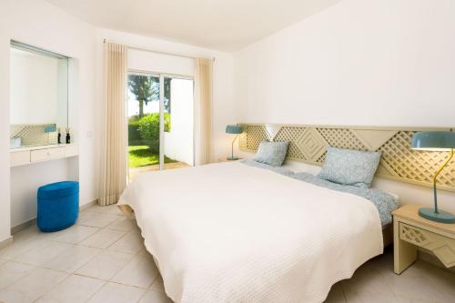 sypialnia z dużym białym łóżkiem i oknem w obiekcie Apartments Maria - Balaia 702 w Albufeirze
