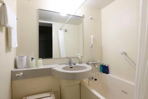 a white bathroom with a sink and a mirror at Hotel Hokke Club Niigata Nagaoka in Nagaoka