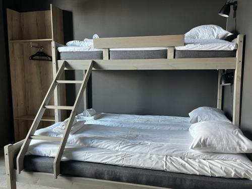 two bunk beds with white sheets and a ladder at Trysil Alpine Lodge in Trysil