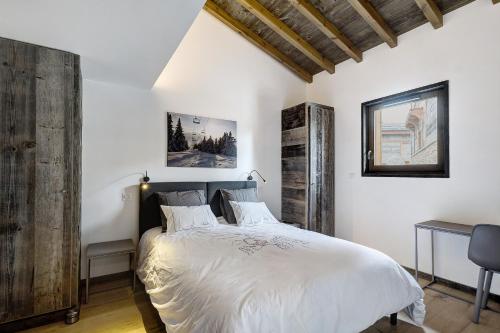 フォン・ロムー・オデイヨ・ヴィアにあるChalet nid des écureuilsの白いシーツと木製の壁のベッド1台が備わるベッドルーム1室が備わります。