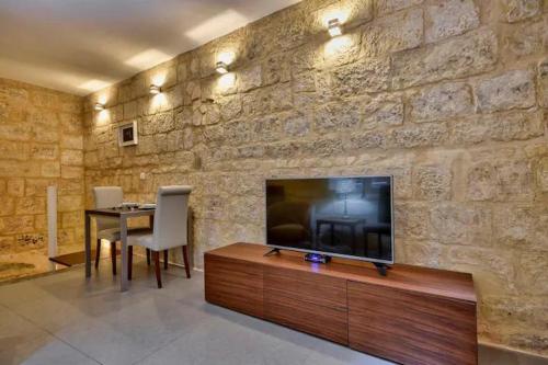 a living room with a television on a stone wall at Cosy 1BR home in the heart of vibrant Valletta by 360 Estates in Valletta