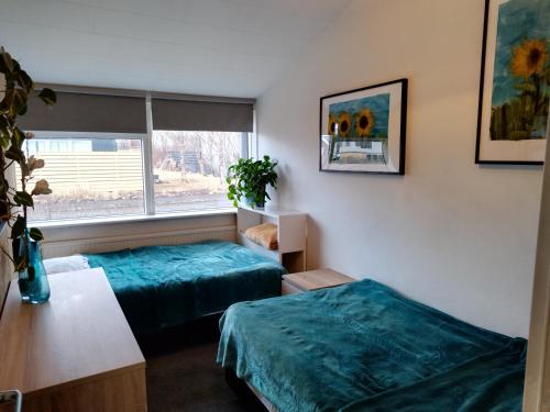 Duas camas num pequeno quarto com uma janela em Charming apartment em Borgarnes