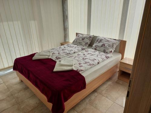 łóżko z czerwonym kocem i poduszkami w obiekcie Szárszó Apartmanok w mieście Balatonszárszó