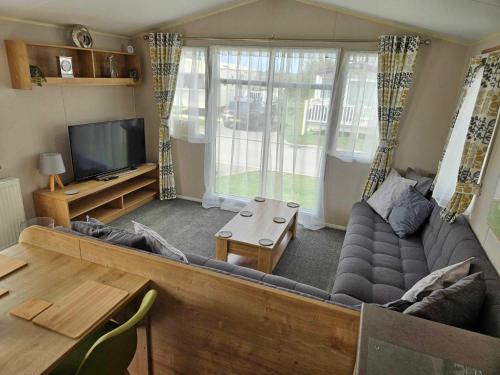 ein Wohnzimmer mit einem Sofa und einem TV in der Unterkunft Luxury Caravan 3 Bedroom 8 Berth With Hot-tub in Lincoln