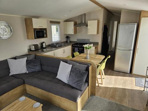 ein Wohnzimmer mit einem Sofa und einer Küche in der Unterkunft Luxury Caravan 3 Bedroom 8 Berth With Hot-tub in Lincoln