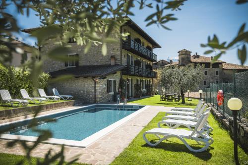 ein Haus mit einem Pool mit Liegestühlen in der Unterkunft Hotel Antica Croce - Gardaslowemotion in Tenno