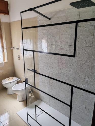 a bathroom with a glass shower door with a toilet at Trapani Emotions apartment in Valderice