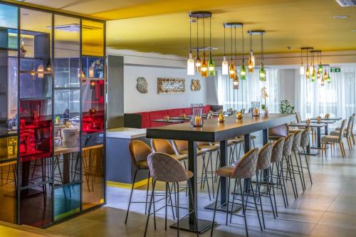 a dining room with a bar with stools at Zsóry Liget Hotel & Spa Superior in Mezőkövesd