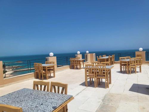 een patio met tafels en stoelen en de oceaan bij SAMA Beach Resort in Hurghada