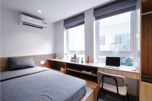a bedroom with a bed and a desk with a laptop at M Village Living Cửu Long in Ho Chi Minh City