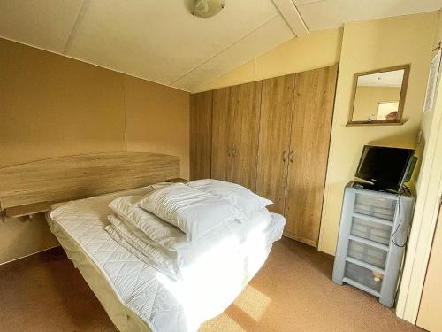 um quarto com uma cama com lençóis brancos e uma televisão em Dog Friendly Caravan With Large Decking Near Heacham Beach, Ref 21052h em Heacham