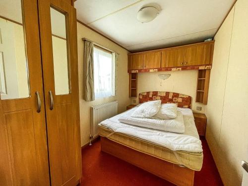 a small bedroom with a bed with white sheets at 8 Berth Caravan For Hire At Heacham Holiday Park In Norfolk Ref 21024f in Heacham