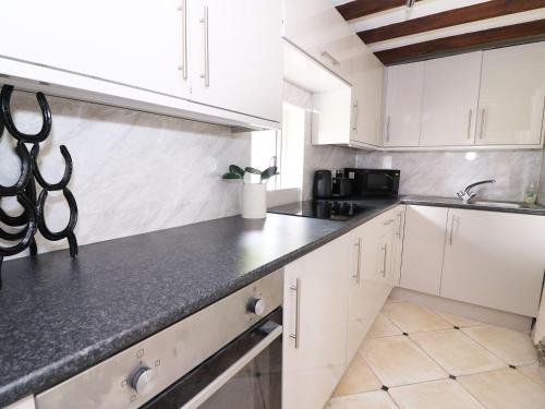 a kitchen with white cabinets and a black counter top at Ty Cloc in Llandysul