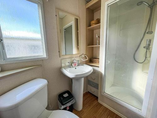 y baño con aseo, lavabo y ducha. en 8 Berth Caravan For Hire By The Beach In Heacham, Norfolk Ref 21038c, en Heacham