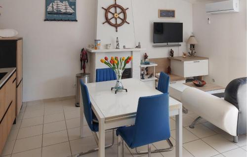 une cuisine et une salle à manger avec une table blanche et des chaises bleues dans l'établissement Gorgeous Home In Notre-Dame-De-Monts, à Notre-Dame-de-Monts