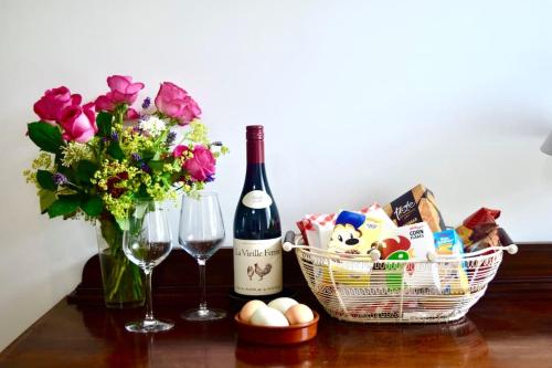 einen Tisch mit einer Flasche Wein und einem Korb mit Blumen in der Unterkunft Stunning stone cottage on Bath's doorstep in Box