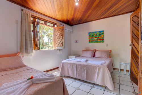 um quarto com 2 camas e uma janela em Pousada casa zaza em Itacaré