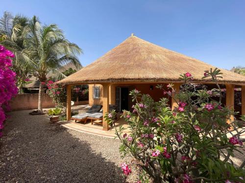 a small hut with a thatched roof and some flowers at Agence Adjana Resort in Saly Portudal