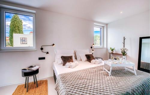ein Schlafzimmer mit einem Bett, einem Tisch und zwei Fenstern in der Unterkunft Nice Home In Biograd Na Moru With Sauna in Biograd na Moru