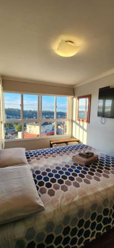 a bedroom with a large bed and a large window at Apto BENTO! LAREIRA e CHURRASQUEIRA! in Bento Gonçalves