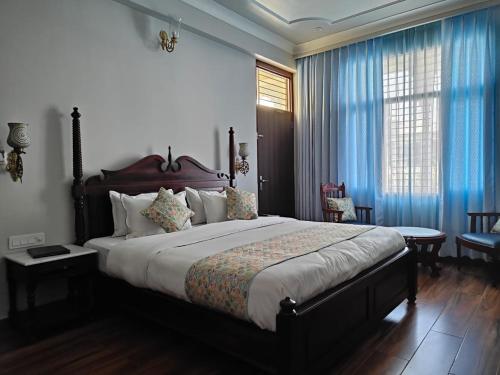 a bedroom with a large bed with blue curtains at Chitawa Haveli - A Luxury Heritage Hotel in Jaipur
